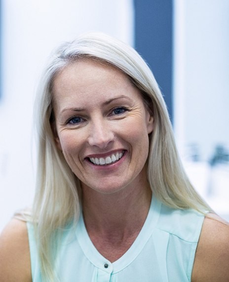 A smiling, middle-aged woman sitting in a dentist’s office