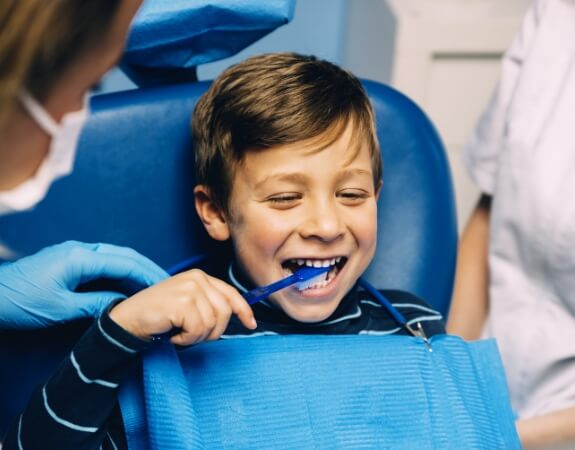 Child learning to brush teeth during special needs dentistry visit