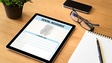 Dental insurance form on tablet with office supplies