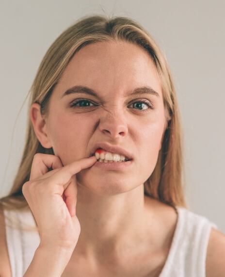 Woman in need of periodontal disease treatment pointing to damaged gum tissue