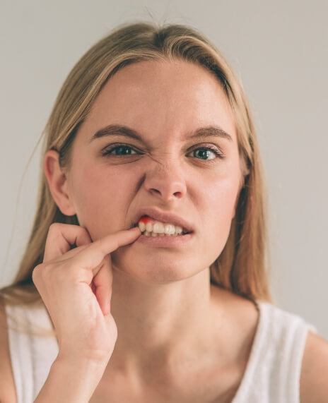 Woman in need of gum disease treatment pointing to damaged gum tissue