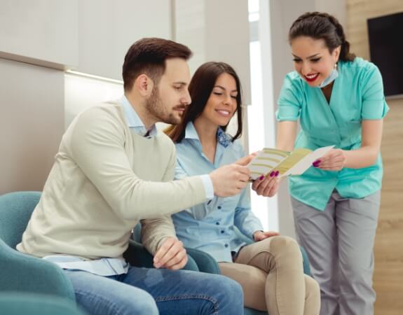 Dental team members and patient reviewing dental insurance forms