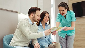 Dental assistant showing couple Invisalign payment information