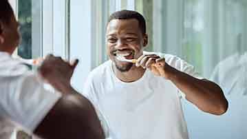 Smiling patient holding clear aligner