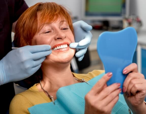 Woman with dentures looking at smile in mirror