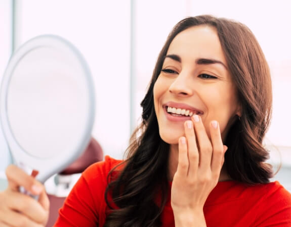 Woman looking at smile after full mouth reconstruction