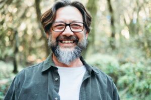 Middle-aged man with glasses smiling. 