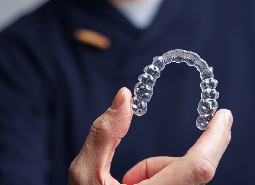 Hand holding clear aligner