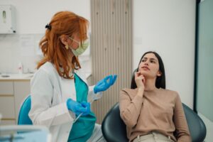 Dentist consulting with patient pointing to her mouth in the dentist’s chair.